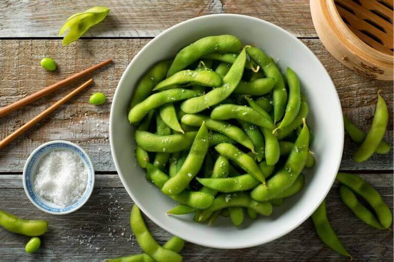 A bowl of salted, steamed soybeans fill a ceramic bowl.