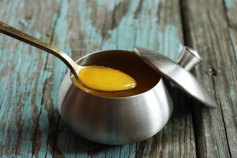 A small teaspoon of liquid clarified butter over a small stainless steel pot.