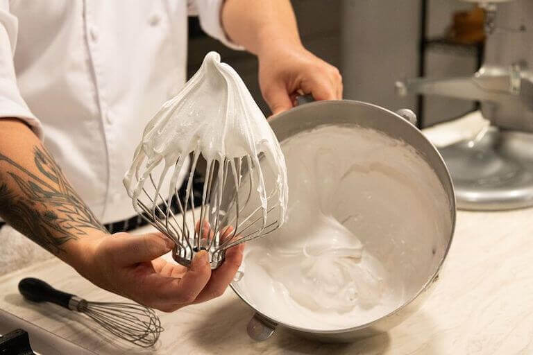 https://www.escoffier.edu/wp-content/uploads/2017/08/Chef-holding-an-electric-mixer-wire-whisk-with-egg-white-peaks-768.jpeg