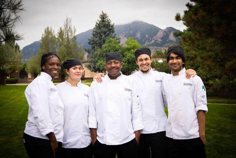 A group of culinary school students stands together at the Escoffier Boulder campus.