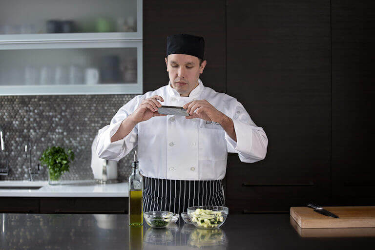 Culinary student taking photo of seasoning and cut vegetables 