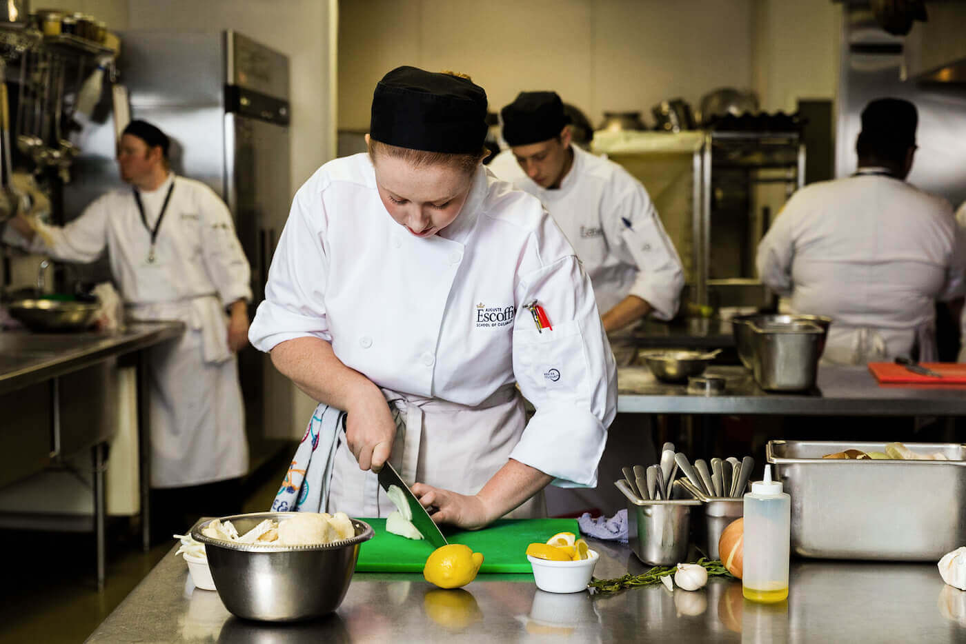 https://www.escoffier.edu/wp-content/uploads/2021/04/Escoffier-student-chopping-an-onion-on-a-cutting-board-in-the-kitchen-1400.jpg