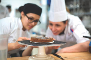 Konditorstudenten, die gebackenes Schokoladendessert betrachten