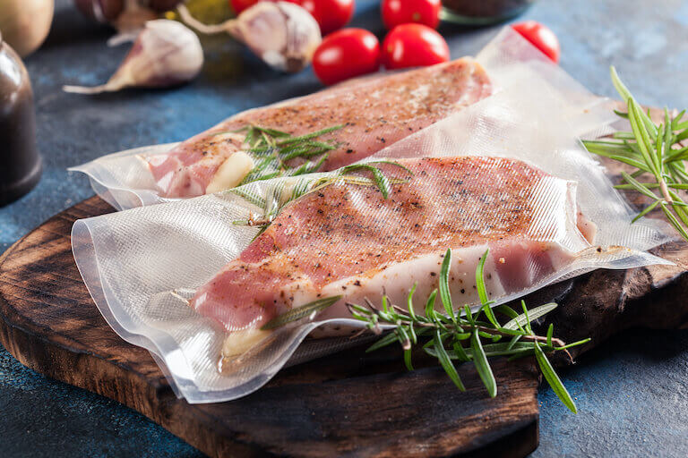 Two pork chops sealed in vacuum-sealed bags, ready for the sous vide bath.