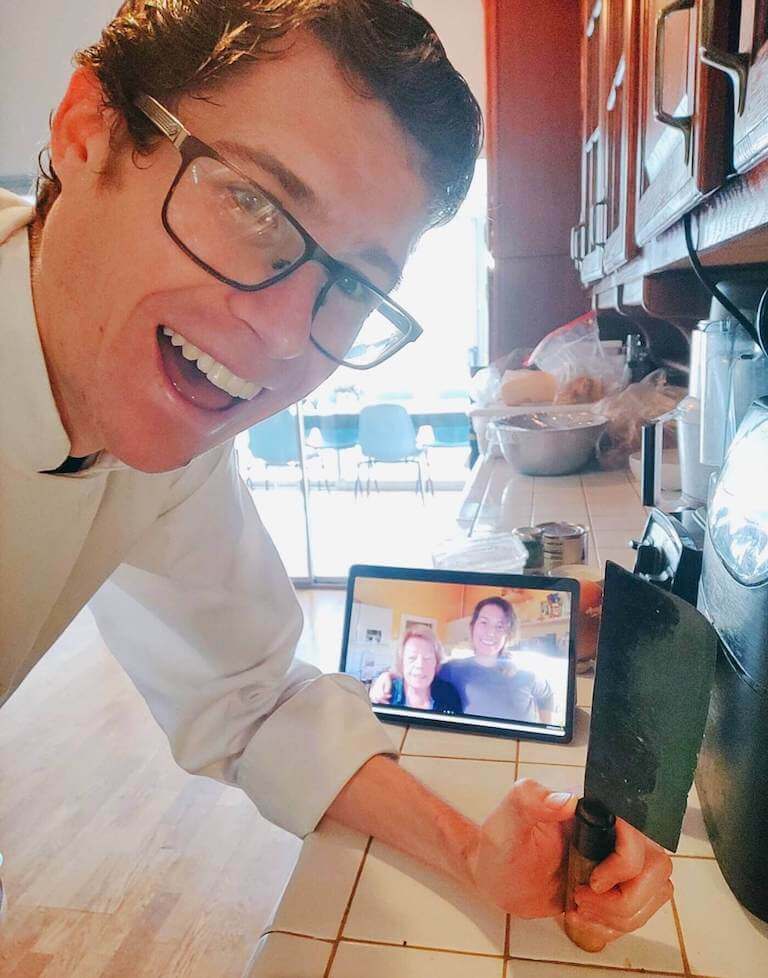 Shane Witters Hicks teaching a cooking class virtually, standing in a kitchen and engaging with students through a video platform.