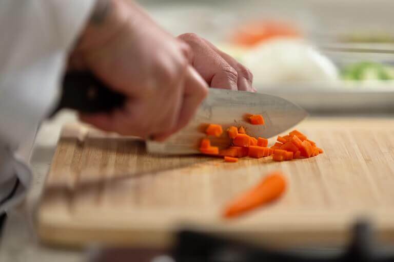 https://www.escoffier.edu/wp-content/uploads/2021/12/Chef-cutting-carrots-on-a-wooden-cutting-board-768.jpg