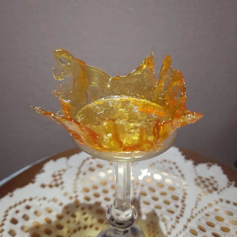 A splash of amber sugar appears frozen in time atop a white pedestal.