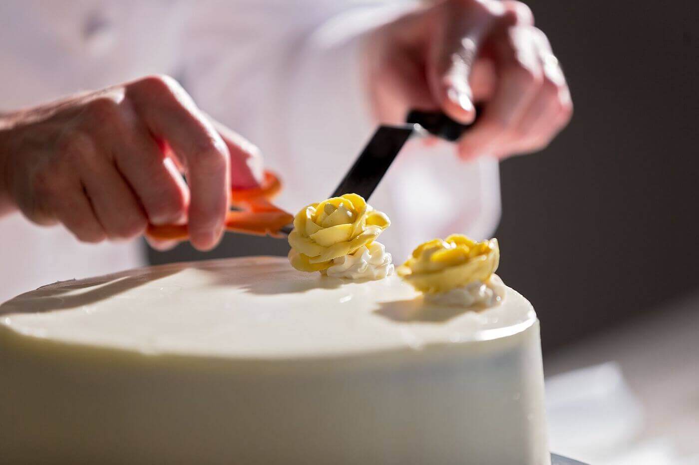 Cake Decorator Placing Yellow Roses On A Cake 1400 