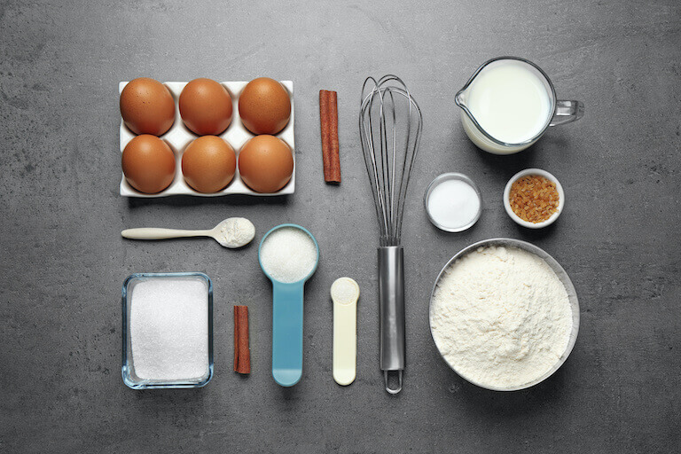 Eggs, flour, sugar, and other baking ingredients laying on a table