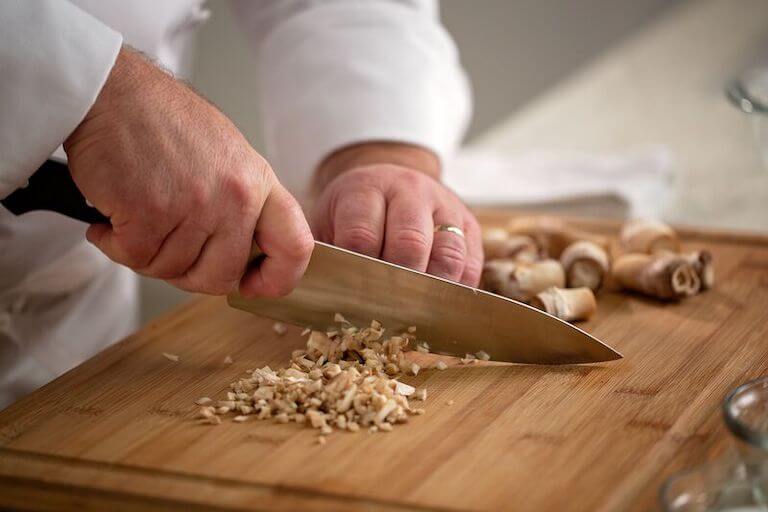 https://www.escoffier.edu/wp-content/uploads/2022/09/Close-up-of-chef-mincing-mushrooms-on-a-wood-cutting-board-768.jpg
