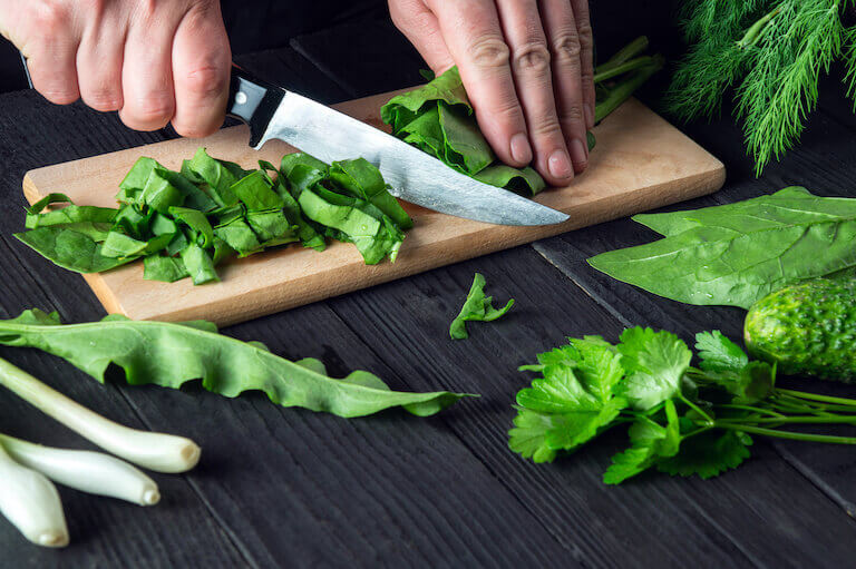 https://www.escoffier.edu/wp-content/uploads/2022/09/Close-up-of-chefs-hands-cutting-spinach-on-a-wooden-cutting-board-768.jpeg