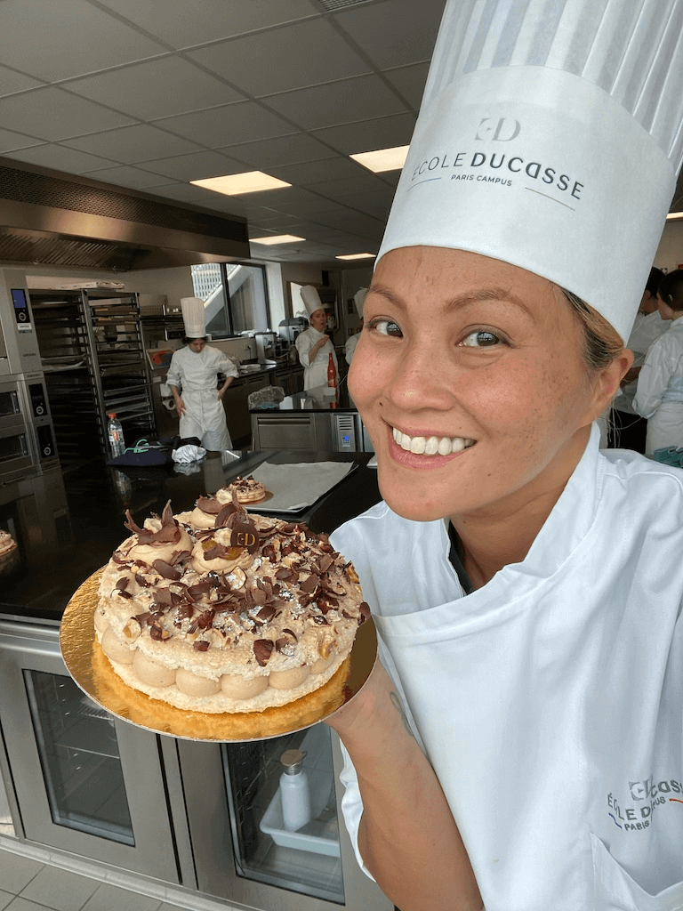 https://www.escoffier.edu/wp-content/uploads/2023/07/Suhalia-holding-a-pastry-in-her-hand-while-working-at-Ecole-Ducasse-768.png