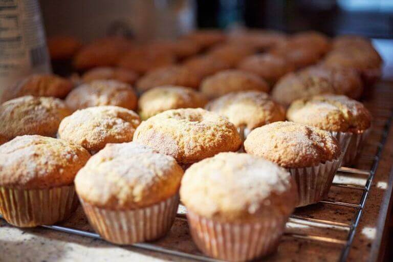 A close-up of coffee cake muffins lined up on a cooling rack. 