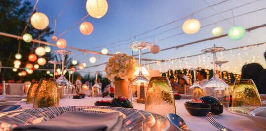 Table setting for an outdoor wedding reception with paper lanterns
