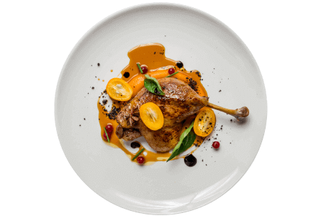 A restaurant plate of chicken quarter with carrots, yellow cherry tomatoes, and demi-glace