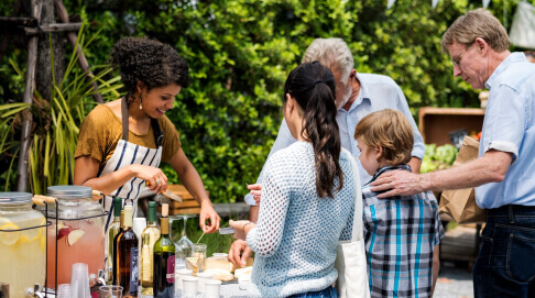 A vendor gives customers cheese tastings at a farmers' market