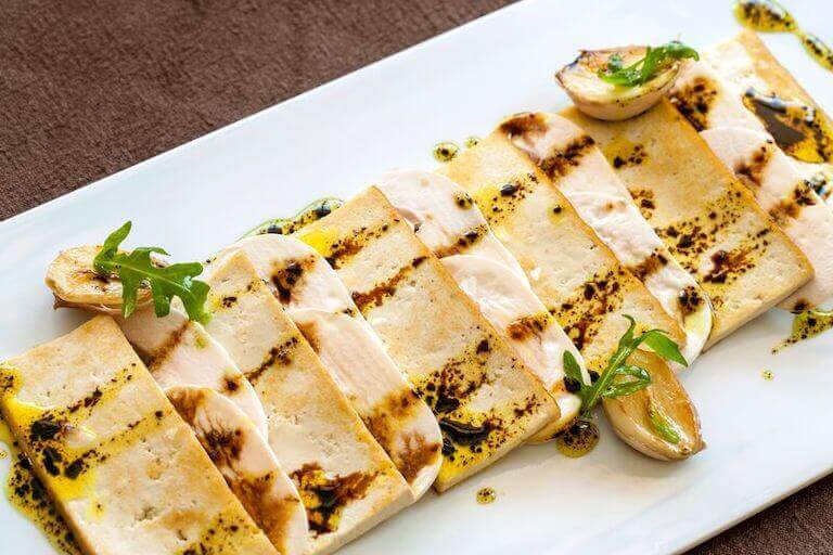 Grilled tofu plated with mushrooms.