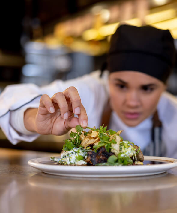 A female chef puts the finishing touches on a gourmet restaurant dish