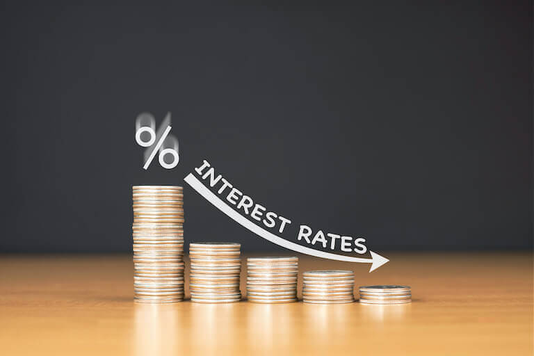 Five stacks of coins in decreasing height, with an arrow pointing down and a graphic saying “Interest rates,” to demonstrate that higher interest rates mean higher payments. 