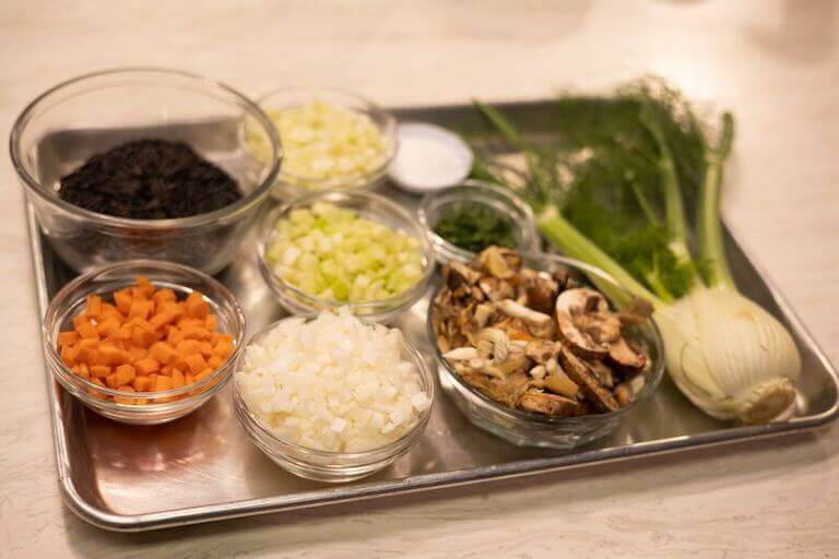 Tray with glass bowls of chopped vegetables prepared to use in soup.