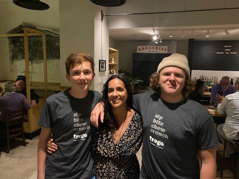 Lolita Sereleas stands in between her two sons, with an arm around their waists. The boys are wearing Trogo tshirts that say, “Sip, Bite, Chew, Crunch.”