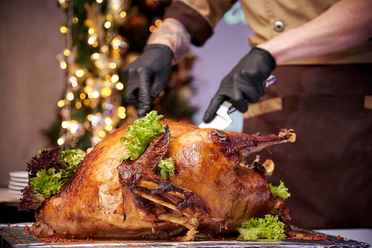 A restaurant worker carves a whole Thanksgiving turkey.