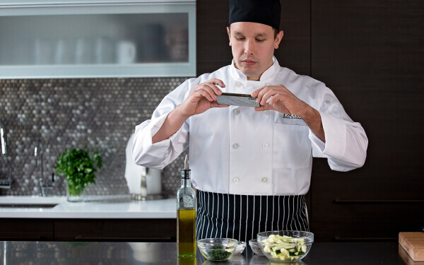 Escoffier online culinary arts student taking a photo of cut vegetables with his mobile phone