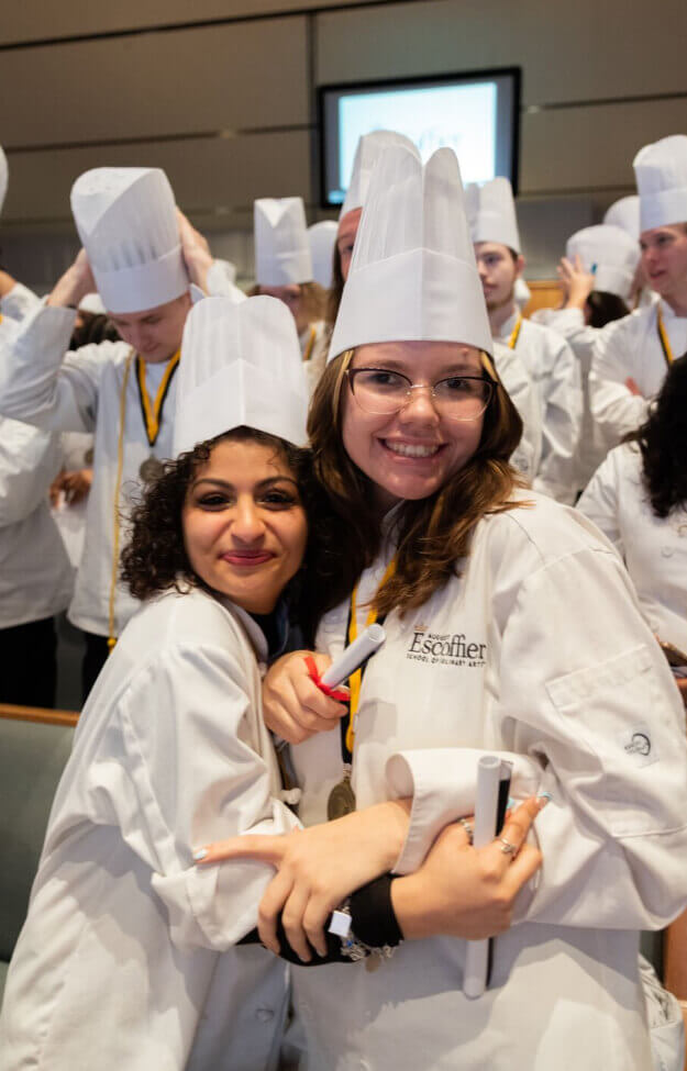 Two Escoffier graduates hug each other at the Escoffier Austin campus graduation ceremony