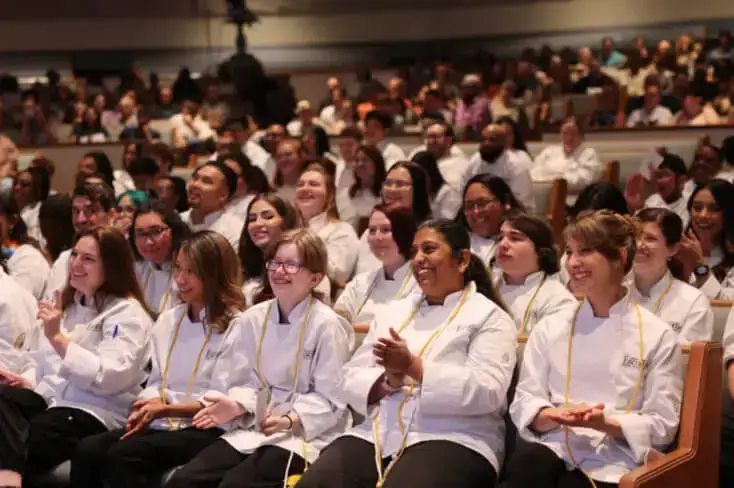 A crowd of Escoffier students smiling at the camera at a graduation ceremony