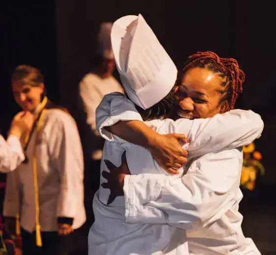 A happy Escoffier graduate hugging the chef instructor after the graduation ceremony