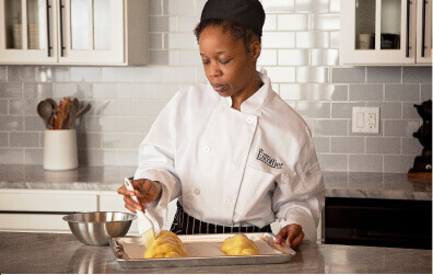 Escoffier online baking and pastry program student spreading butter on challah bread dough in her home kitchen